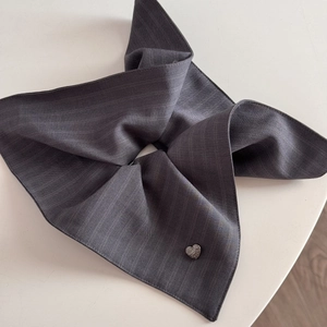 Detail of dark grey striped fabric scrunchie featuring a small sparkly heart charm