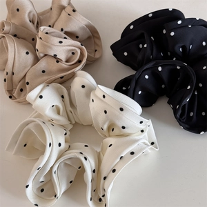 Flat lay of satin polka dot scrunchies in beige, black and white colors