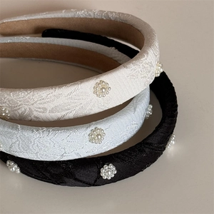Three elegant vintage style pearl flower headbands in beige, light blue, and black fabric