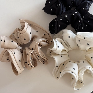 Detailed view of satin polka dot scrunchies in black, khaki, and cream colors