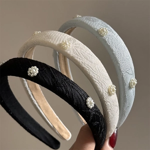Detail of embroidered floral sponge headbands with pearls in black, beige, and blue