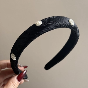 Detail of black satin headband with sponge padding and delicate pearl flower embroidery