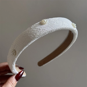 Detail view of Chinese style floral embroidery and small pearl clusters on the sponge headband