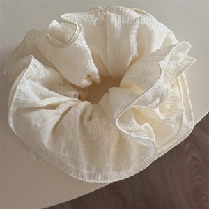 Close-up of cream white oversized scrunchie showing ruffled fabric texture and fine stitching