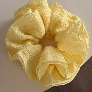 Macro shot of large pale yellow scrunchie featuring textured seersucker fabric detail