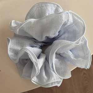 Macro detail of a light blue ruffled scrunchie made of premium seersucker fabric texture
