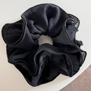 Detailed macro view of the black oversized scrunchie showing fine pleated fabric texture