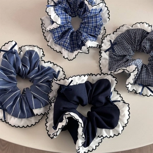 Detailed view of blue plaid and striped scrunchies with white lace edges and small bows