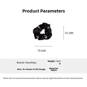 Detailed view of black fabric scrunchie featuring pink cherry embroidery and side label