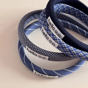 Detailed view of four blue plaid and striped fabric headbands with hello smile labels