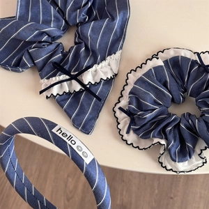 Detailed close-up of blue striped fabric scrunchie with lace trim and ribbon bow