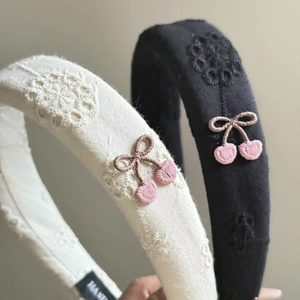 Detail of embroidered floral headbands with 3D knitted cherry bow and hand label