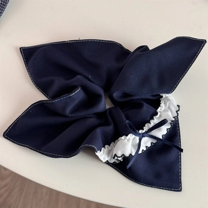 Detailed view of navy blue plaid hair scrunchie with white lace trim and bow accent