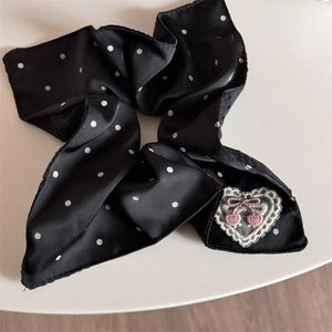 Close-up of black polka dot satin scrunchie with lace heart and cherry embroidery detail