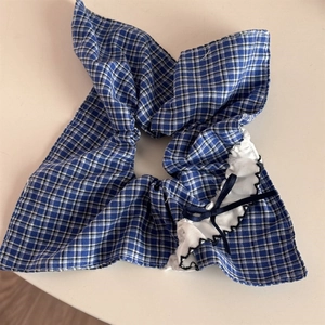 Close-up of blue plaid scrunchie with white ruffled edges and a navy ribbon bow detail