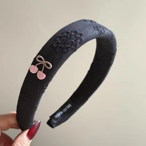 Detail of black fabric headband featuring delicate floral and pink cherry embroidery