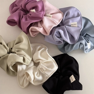 Detailed shot of assorted candy-colored fabric scrunchies with Hand Made woven labels