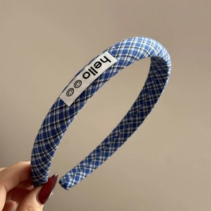 Close-up of blue plaid headband with hello label and smiley icons on fabric