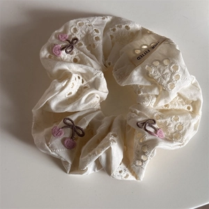 Detail of white cotton scrunchie with hollow floral embroidery and cherry patterns