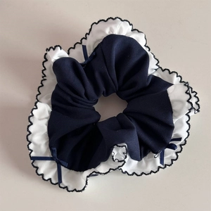 Detail of blue and white ruffled scrunchie with navy ribbon bows and wavy edges