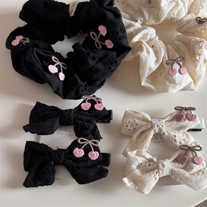Detail of embroidered cherry patterns and hollow-out lace on white and black hair ties