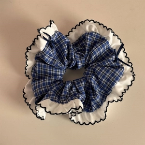 Detail of blue plaid scrunchie with white ruffled edges and black wave stitching