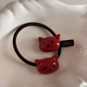 Gros plan d'un accessoire cheveux chat rouge sur une assiette blanche texturée