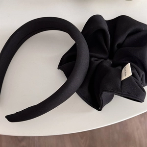 Detail of black ribbed fabric padded headband and large scrunchie with handmade tag