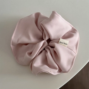 Close-up of pink scrunchie with twill texture and Hand Made fabric label detail