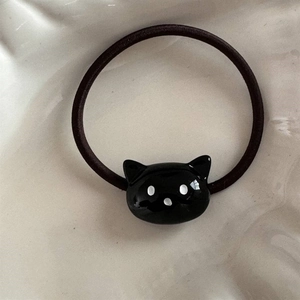 Détail macro d'un élastique noir avec un joli ornement de chat noir en résine