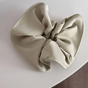 Detail of a beige scrunchie with twill fabric texture and durable elastic band interior