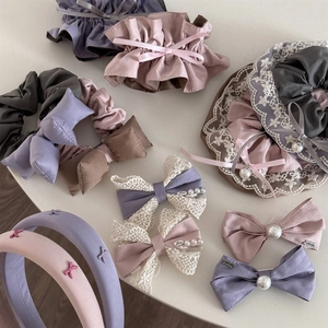 Flat lay of purple lace bow scrunchies and satin hair accessories with pearl details