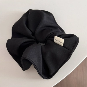 Detailed macro view of black sponge headband showing handmade label and fabric texture