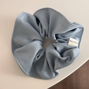 Detailed texture of blue cotton scrunchie with a white Hand Made textile label