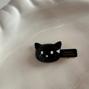 Détail d'une pince à cheveux chat noir faite main avec logo France doré sur acétate