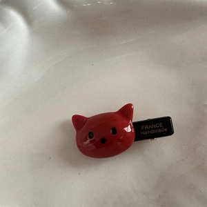 Détail d'une pince à cheveux chat rouge avec texte France Handmade sur céramique