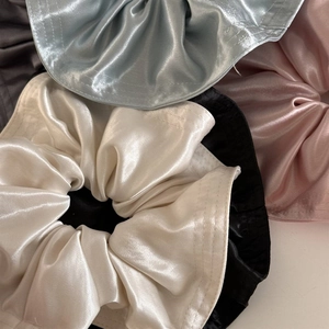 Close-up of premium satin hair scrunchies with elegant glossy texture and pleated detail