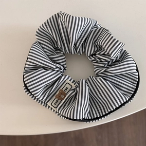Close-up of black and white striped scrunchie with cute bear logo fabric label