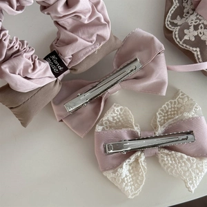 Detailed view of pink satin scrunchie with lace trim and elegant bow hair clips