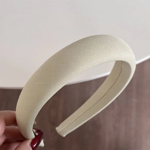 Close-up of beige padded sponge headband featuring a thick design and textured fabric