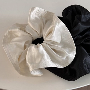 Close-up of premium satin scrunchies in cream and black showing detailed silk texture