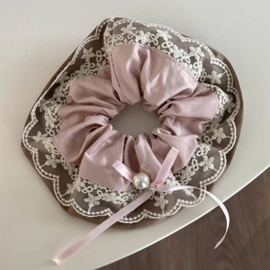 Detail of pink satin scrunchie with white floral lace trim, ribbon bow and pearl pendant