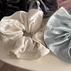 Detail showing the fine stitching and glossy texture of satin silk scrunchies in multiple colors