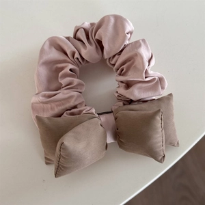 Detailed view of pink lace scrunchie with silky brown bow featuring soft luster and texture