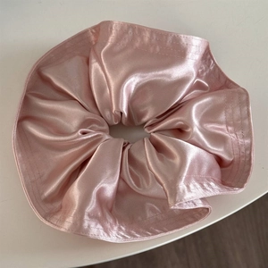 Detailed view of large pale pink satin scrunchie with soft pleats and a silky pearl sheen