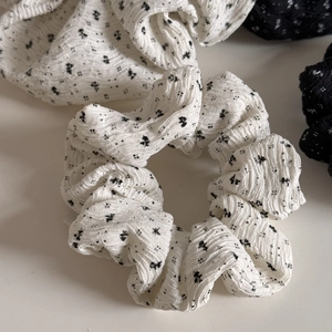 Detailaufnahme eines floralen Haargummis mit schwarz-weißem Muster aus Stoff
