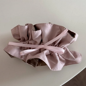 Detail shot of pink and brown satin fabric scrunchie with silk ribbon bow accessory