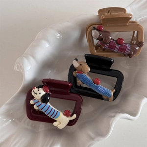 Detailed view of three cute cartoon dachshund hair clips in a white shell-textured tray