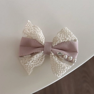 Close-up of pink and cream lace bow hair clip with pearls and Love metal pendant