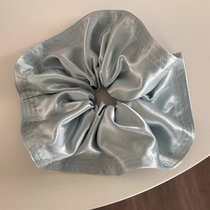 Detail view of light blue satin scrunchie with shiny silk texture and visible stitching